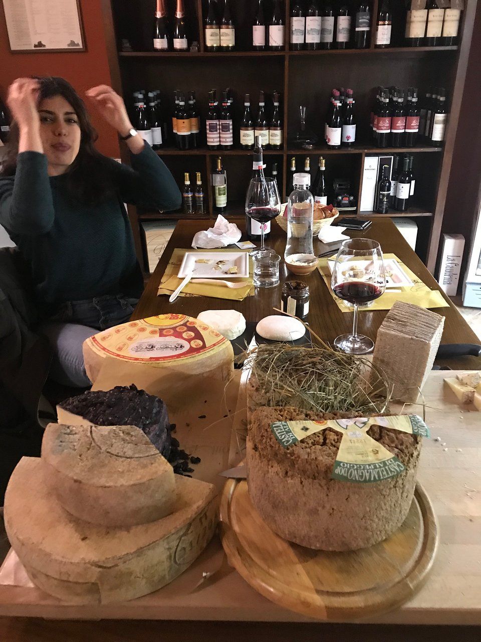 Mulher bebendo vinho ao lado de rodas de queijo