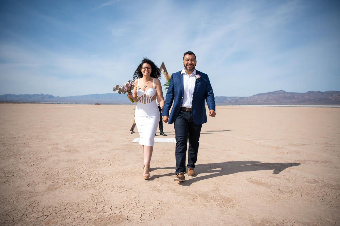 Casal de noivos andando no deserto