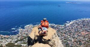 a hiker taking in the views of cape town at the summit of lions head