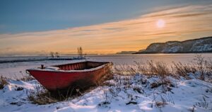 a row boat on the shore of thunder bay covered in snow
