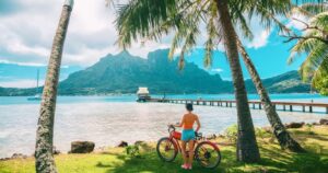 a woman standing with a bike at a beach in hawaii