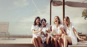 Cheerful bride and bridesmaids celebrating hen party with champagne