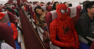a man dressed up as spiderman gets on a plane with someone dressed like mario
