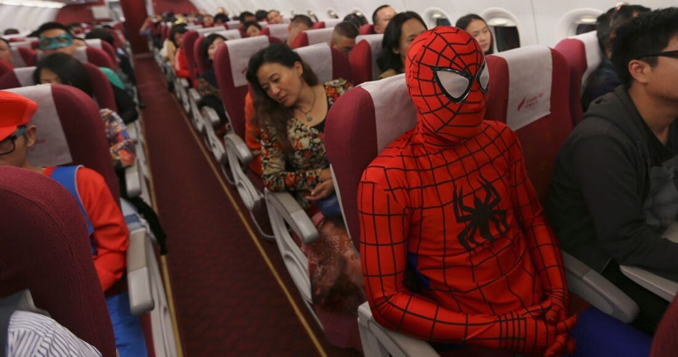 um homem vestido de homem aranha entra em um avião com alguém vestido de mario