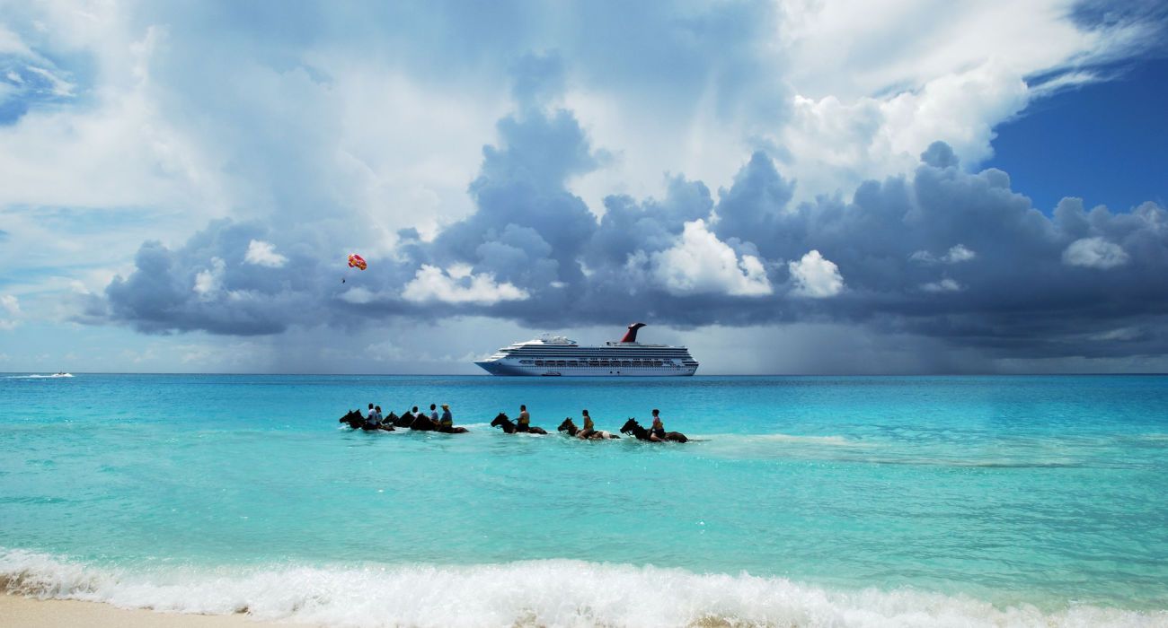 O grupo de turistas andando a cavalo no mar do Caribe em Half Moon Cay