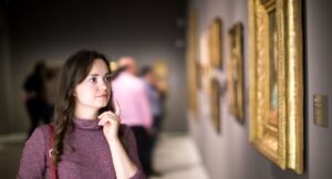 girl attentively looking at paintings in art museum